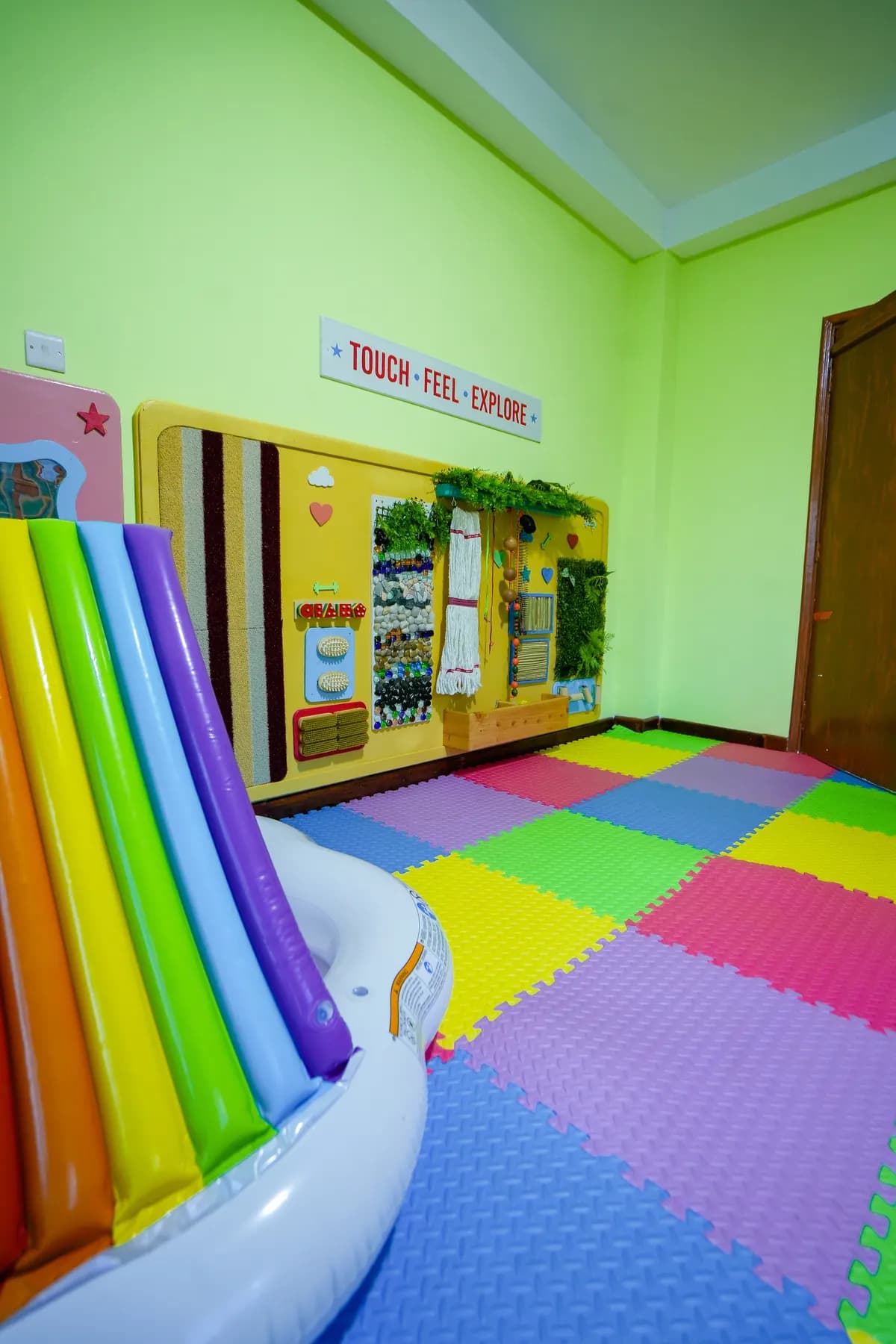 Touch, feel and explore sensory wall beside a rainbow slide