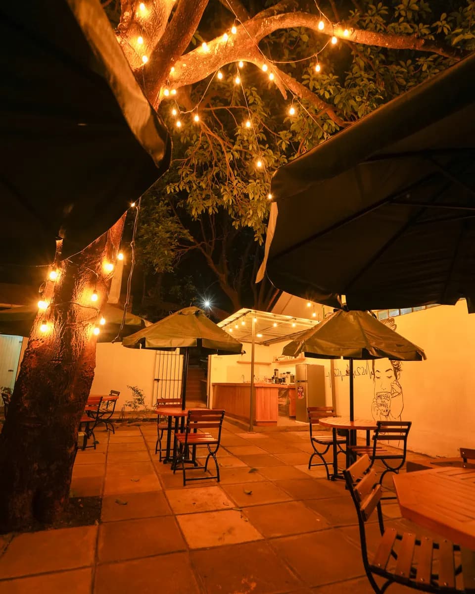 The coffee shop terrace lit up at night with string lights and umbrellas