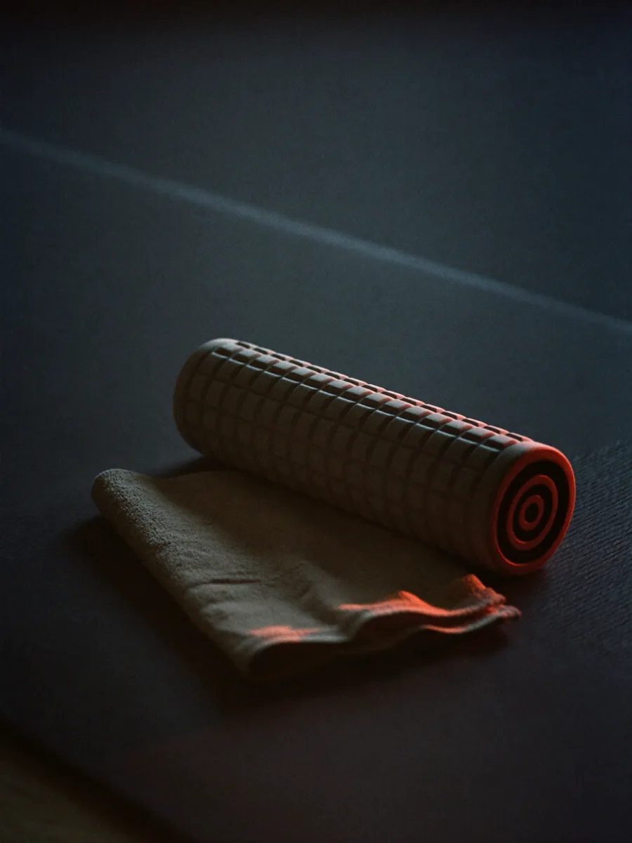 A foam roller and towel resting on a gym mat